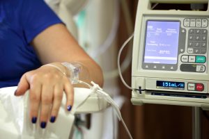 Infusion pump feeding IV drip into patients arm focus on needle